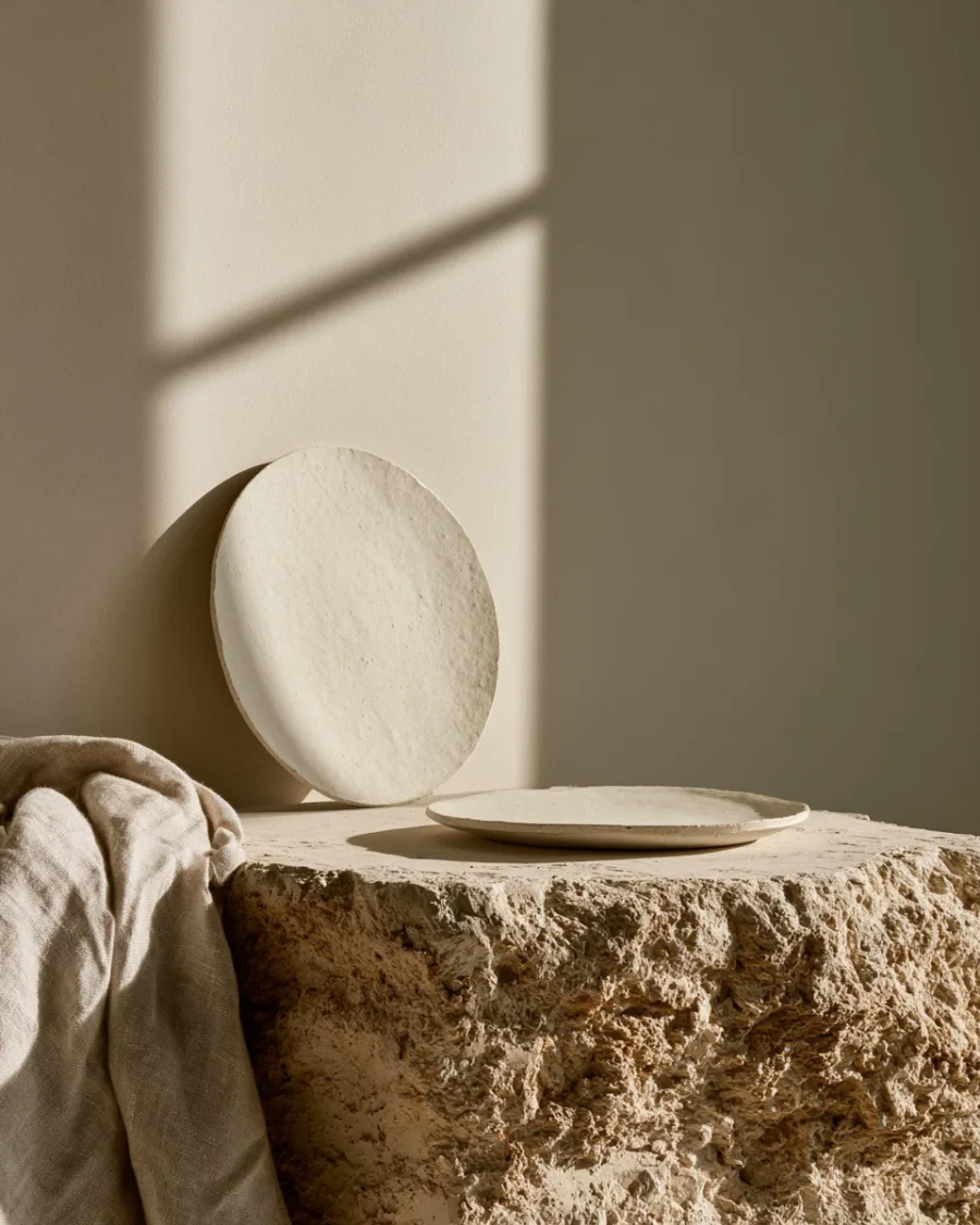Ash-glazed side plate propped upright against plaster