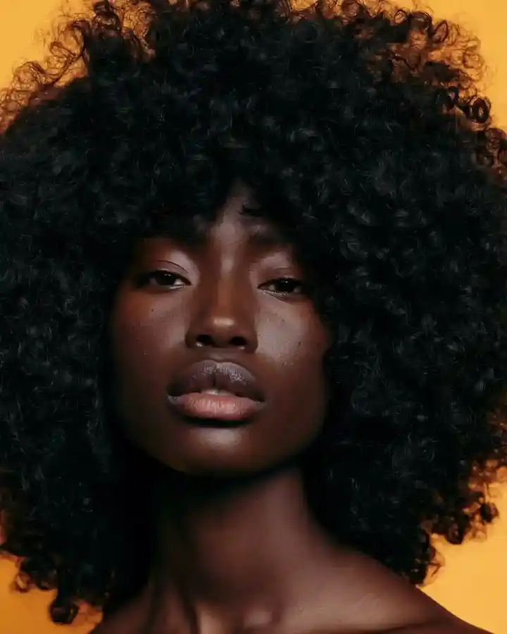 Close afro portrait against a warm amber backdrop