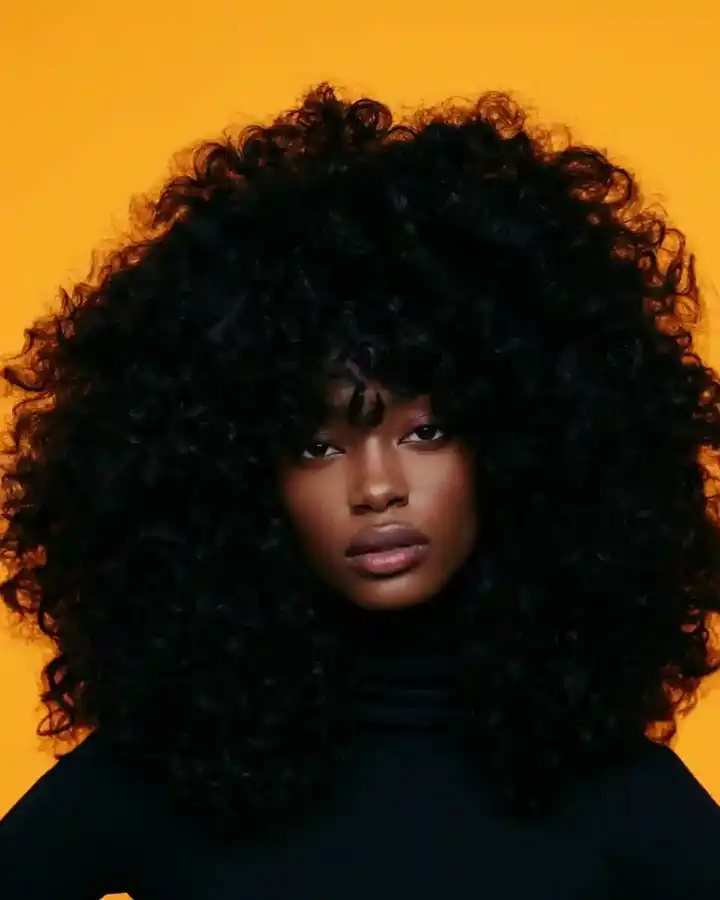 Dark afro lit from the side against amber