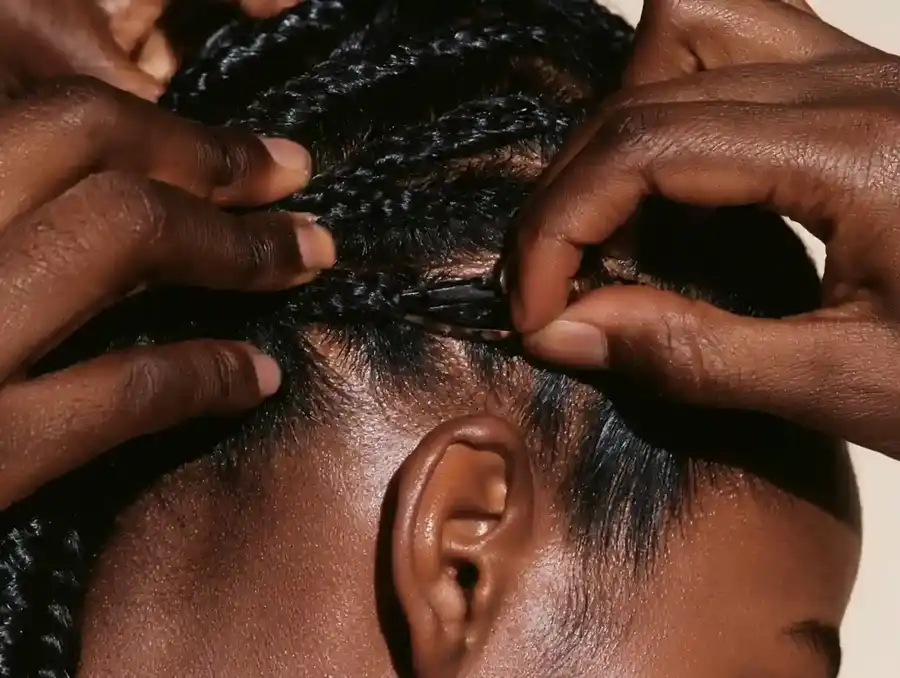 Hands clipping a hairpiece into flattened braided hair