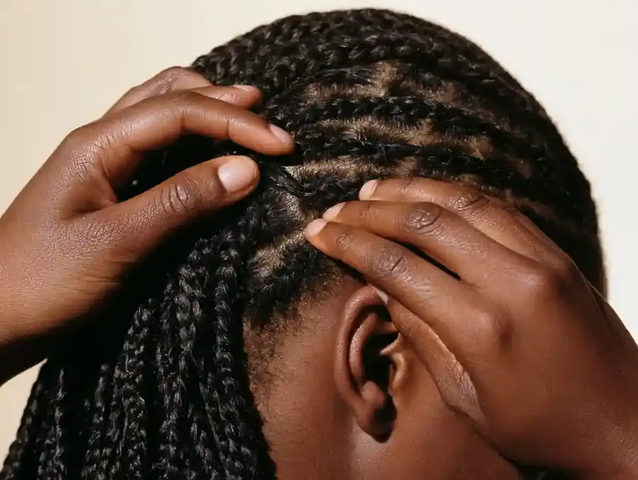 Hands clipping a hairpiece into flattened braided hair
