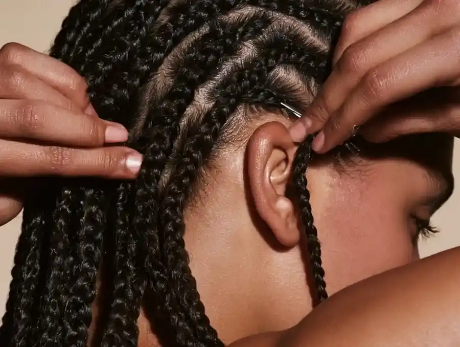 Hands clipping a hairpiece into flattened braided hair