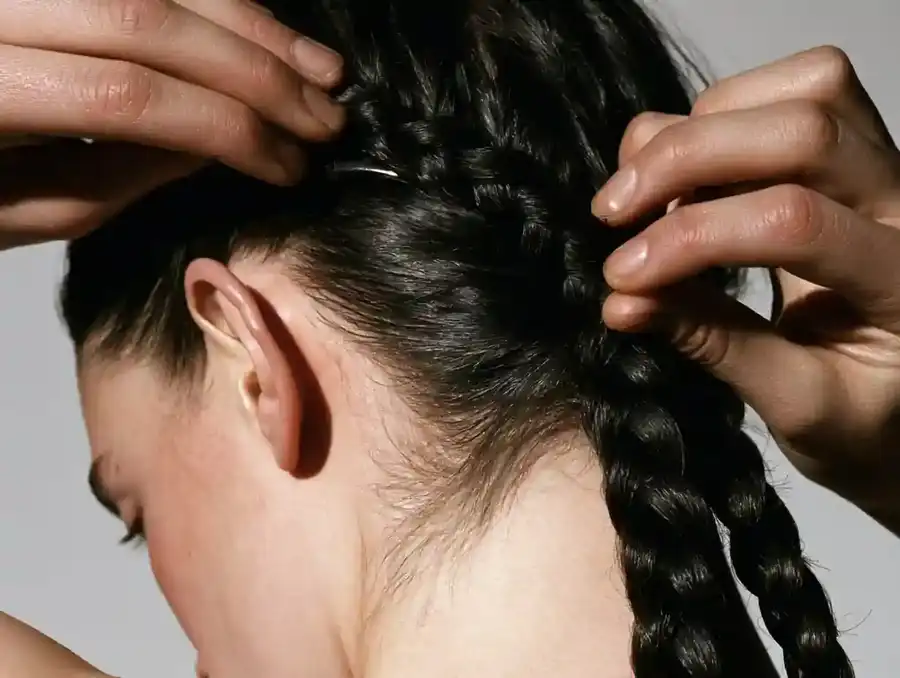 Hands clipping a hairpiece into flattened braided hair