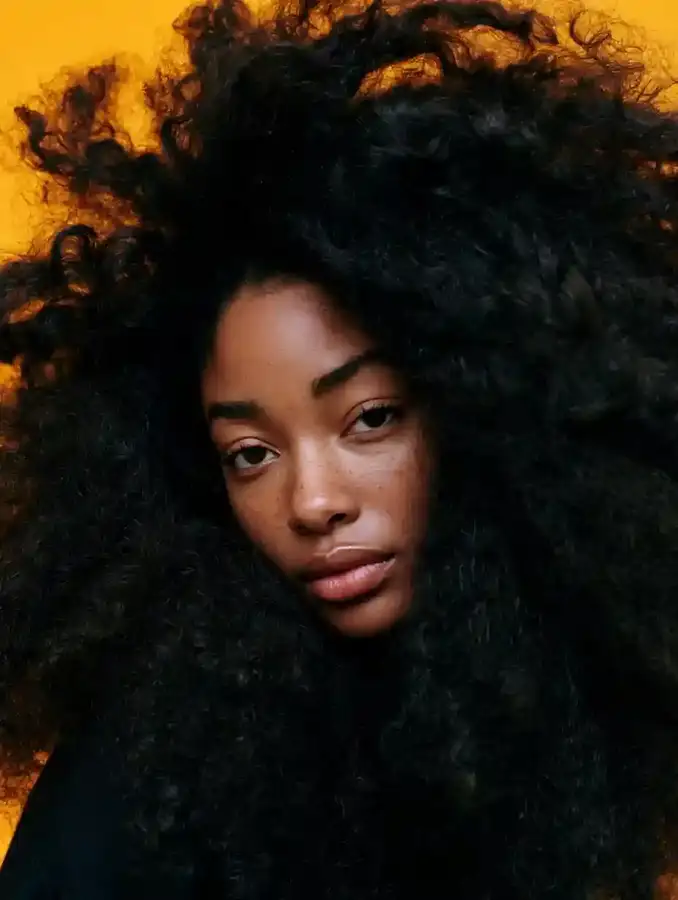 Curly hair portrait against a saffron backdrop