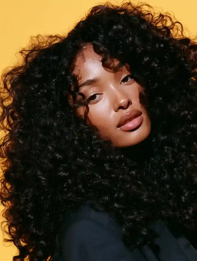 Curly hair portrait against a saffron backdrop