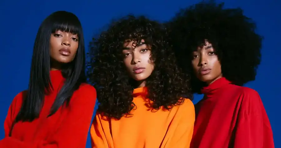 Three models in different curl patterns against a blue backdrop, wide frame