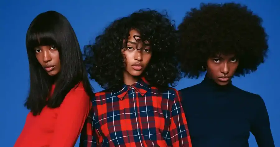 Three models in different curl patterns against a blue backdrop, wide frame