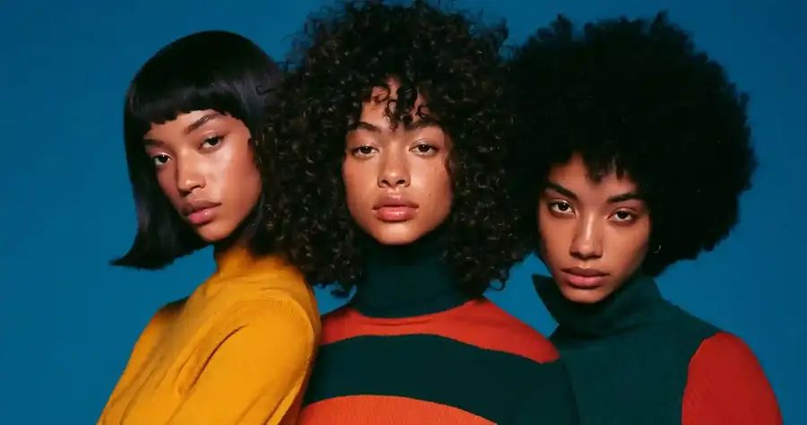 Three models in different curl patterns against a blue backdrop, wide frame