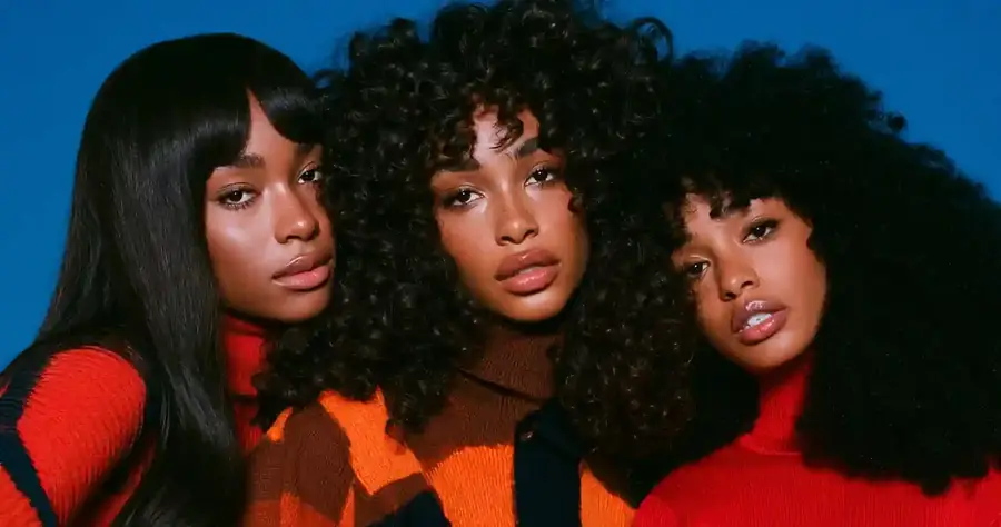 Three models in different curl patterns against a blue backdrop, wide frame
