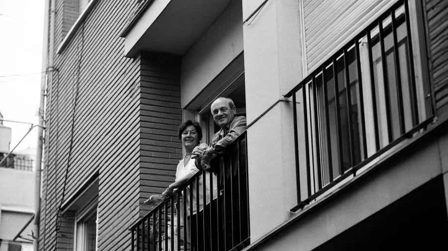 Smiling couple in their fifties on the balcony of a Madrid apartment block
