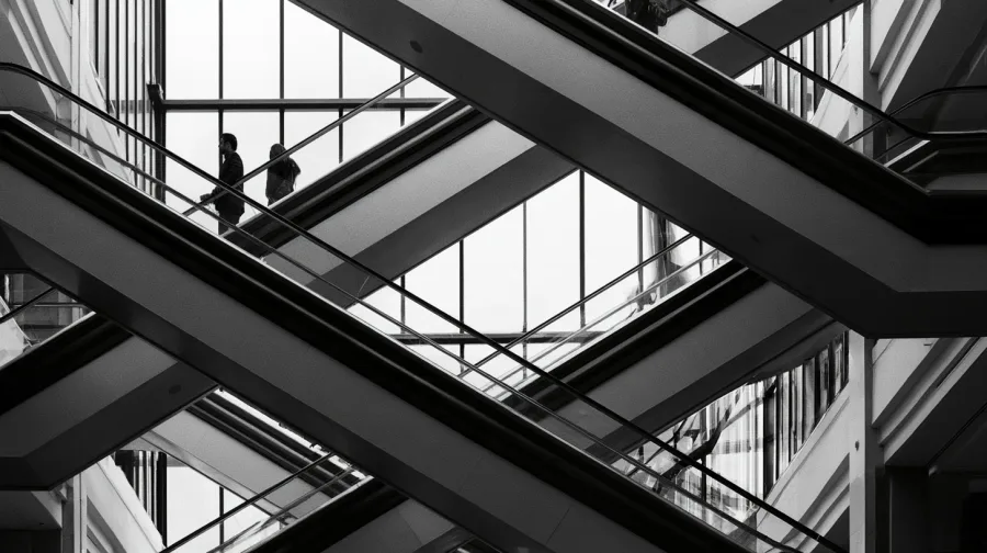 Criss-crossing department store escalators seen from below through a glass atrium